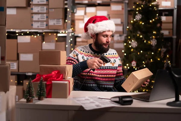 配達小包のサンタスキャンバーコード 労働者はクリスマスに働く貯蔵で配達の前に段ボール パッケージのバーコードをスキャンします ボックス上の男性マネージャーの工場倉庫スキャンラベル — ストック写真