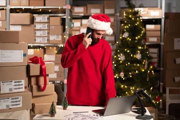 Noel 'de depoda dizüstü bilgisayarla çalışırken cep telefonuyla konuşan mutlu girişimci. Çevrimiçi mağaza sahibi sevkiyat siparişi verecek. Küçük bir e-ticaret şirketi işleten bir iş adamı. Boşluğu kopyala