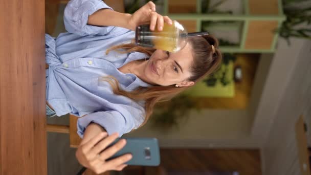 魅力的な若い女性の旅行者は カフェでバブルティーでセルフィーを取るためにスマートフォンを使用しています バーティカルビデオ — ストック動画
