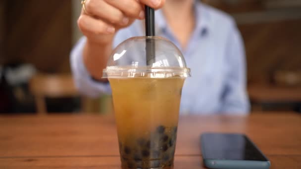 一个在咖啡馆里喝泡泡茶的女孩从桌子上拿起一个塑料杯 这是特写 复制空间 — 图库视频影像