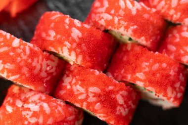 Somon ve kırmızı havyarlı suşi rulosu. Siyah panoya yakın çekim, üst manzara. Boşluğu kopyala