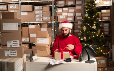 İş kurma KOBİ konsepti genç erkek girişimci, küçük işletme sahibi, ambalaj malzemeleri, depoda çalışmaya hazırlanan sevkiyat. Noel sezonu indirimi. Boşluğu kopyala