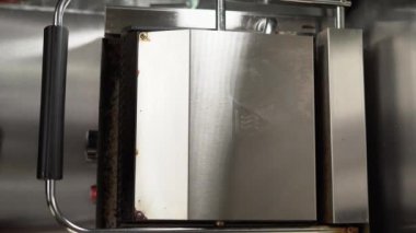 Bir kafede elektrikli ızgarada sosisli ekmeği ısıtıyorum. Yukarıdan bak. dikey video