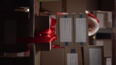 Depo işçisi raflarda kutular dolusu kutular arıyor. Postane çalışanı için kayıp paketler, Noel hediyesi. Uzayı kopyala Dikey video