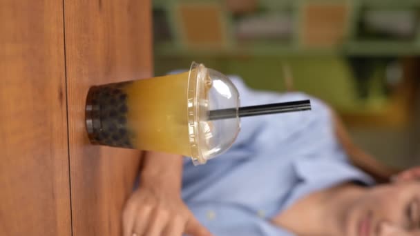 年轻女人喝茶泡泡 在餐馆或咖啡馆里用智能手机享受假期 垂直录像 — 图库视频影像