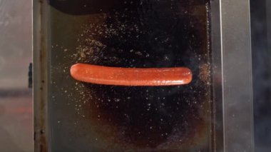 Elektrikli ızgarada bir sosis kızartması, üst manzara. Fast food sosisli sandviçi için otomatik barbekü. Dikey video