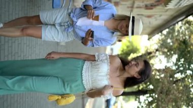 İki kadın arkadaş ellerinde dondurmayla şehirde yürüyor ve tatilin tadını çıkarıyorlar. Dikey video