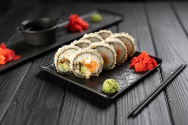 Kızarmış suşi, somon balığı ve siyah arka planda Philadelphia krem peyniri. Ton balıklı sıcak tempura suşi seti ve taş levhada Norveç yosunu. Boşluğu kopyala