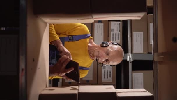 Oude Mannelijke Werknemer Draagt Headset Logistiek Magazijn Met Behulp Van — Stockvideo