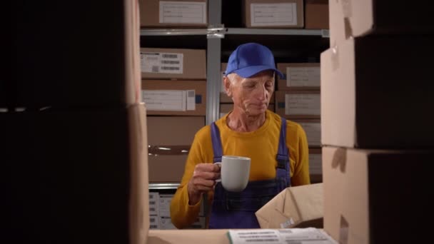 倉庫労働者の高齢者は 船積み箱でコーヒーを飲んでいる コピースペース — ストック動画