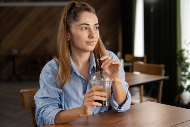 Bir kafede köpüklü çay içen genç bir kadın başka yöne bakıyor ve düşünüyor. Boşluğu kopyala