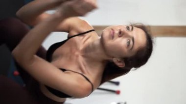CrossFit sağlıklı yaşam tarzı konsepti. Spor tişörtlü spor kaslı bayan mekik çekiyor. Dikey video