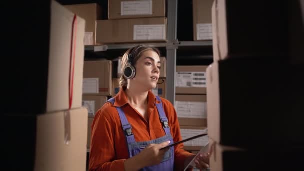 工場倉庫のクリップボードにヘッドセットを書いている倉庫の女性マネージャー コピースペース — ストック動画