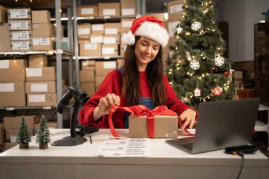 Noel Baba hediye paketini kırmızı kurdeleyle paketliyor. Posta teslimat paketini hazırlıyor. Noel sevkiyatı. Boşluğu kopyala
