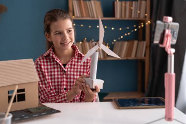 Ekoloji, teknoloji ve enerji tasarrufu kavramı. Genç blogcu evinden rüzgar türbinleri projesiyle ilgili video kaydediyor. Boşluğu kopyala