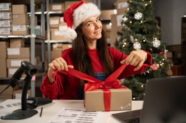 Noel Baba hediye paketini kırmızı kurdeleyle paketliyor. Posta teslimat paketini hazırlıyor. Noel sevkiyatı. Boşluğu kopyala