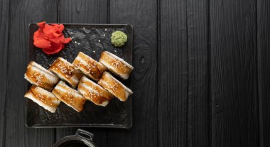 Siyah taştan bir tabakta yılan balıklı lezzetli suşi ruloları, üst manzara. Geleneksel Japon yemekleri. Uzayı kopyala Pankart