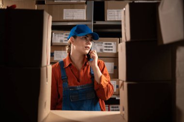 Perakende satış merkezinde telefondaki müşterinin siparişlerini doğrulayan genç bir satıcı konuşuyor. Dağıtım ve Lojistik kavramı