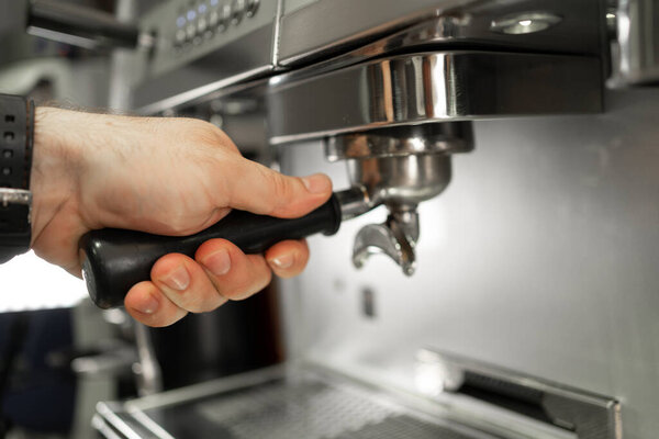 Close-up of barista inserting portafilter into coffee machine espresso making process. Copy space