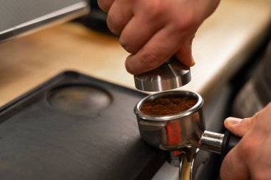 Barista portafilter tutuyor ve kahve karıştırıcı kahve yapıyor. Kafede, yakın plan. Boşluğu kopyala