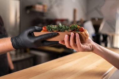 Erkek aşçı elleri yemek kamyonundan bir kadına sosisli verir. Sokak yemekleri ve fast food konsepti.