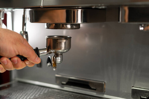 Stainless steel portafilter with ground coffee. Espresso machine parts. Coffee machine in coffee shop. Close-up