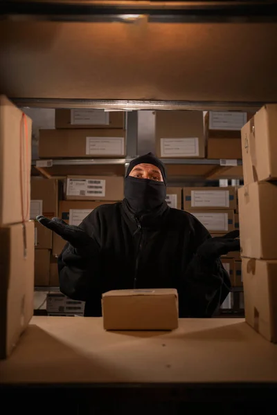 Thief caught red-handed in a warehouse with cardboard boxes, warehouse and store security concept. Copy space