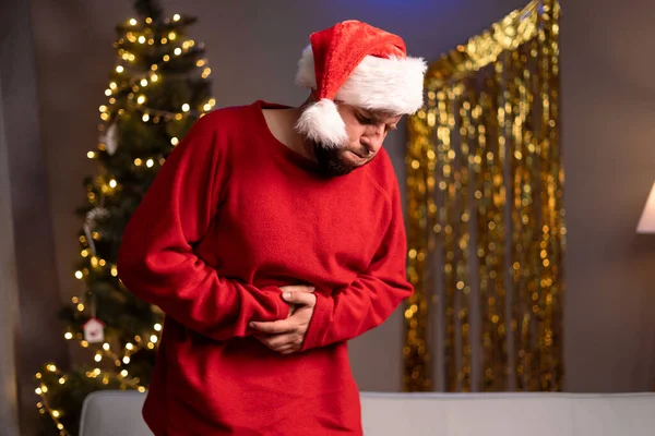 아늑한 거실에서 불행한 남자는 고통에서 크리스마스에 중독과 경련을 겪고있다 — 스톡 사진