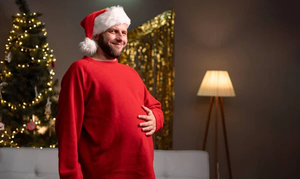 Man in santa hat with big belly overeating at party. Copy space