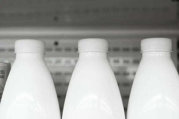 stock image Close-up of many milk bottles with white caps standing in a row in supermarket. Copy space