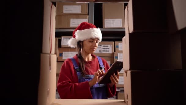 Складський Робітник Санта Капелюсі Використовує Цифровий Планшет Перевірки Акцій Різдвяних — стокове відео