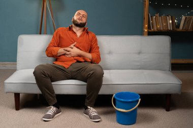 Hasta adam hasta midesinden muzdarip ve evinde koltuğa kusuyor. Boşluğu kopyala