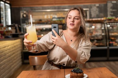 Akıllı telefonuyla kokteyl fotoğrafı çeken çekici bir kız. Lokantada ateş eden yemek blogcuları. Boşluğu kopyala