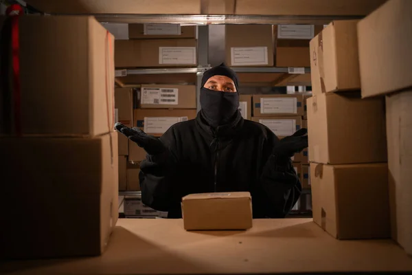 Thief caught red-handed in a warehouse with cardboard boxes, warehouse and store security concept. Copy space