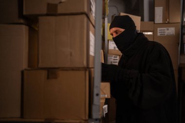 Depo hırsızı gece kutu kutu mal çalıyor. Malların çalınması ve ambarlardaki posta paketlerinin çalınması kavramı. Boşluğu kopyala