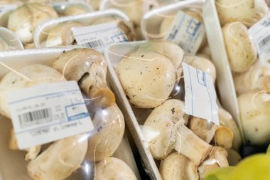 Plastik pakete sarılı beyaz mantarlar pazarda satılıktır. Yakın plan.