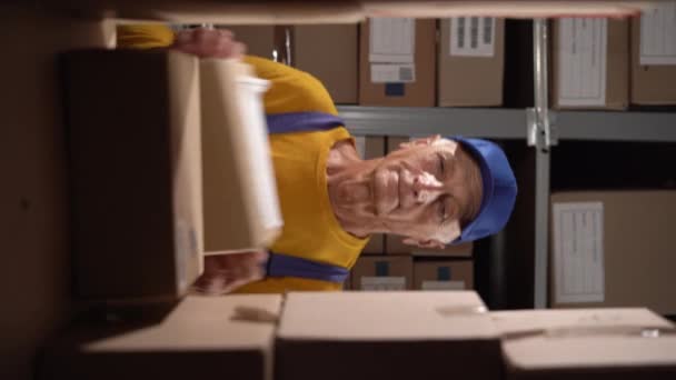 오래된 노동자는 사이에 서있는 선반에 상자를 넣습니다 비디오 — 비디오