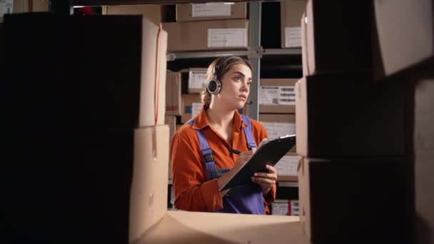 Female Professional Operator Wearing Headset Standing Next Shelf Counting Parcels — Stock Video