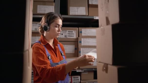 保管庫のクリップボードにヘッドセットを書いている倉庫のマネージャー コピースペース — ストック動画