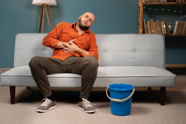 Hasta adam hasta midesinden muzdarip ve evinde koltuğa kusuyor. Boşluğu kopyala