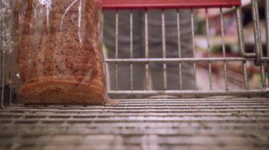 Genç bir kadının elleri cam bir kavanoza konserve yeşil bezelye koyarak alışveriş arabasına yaklaşır. Boşluğu kopyala.