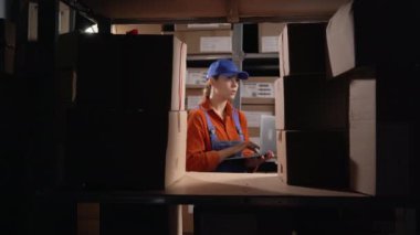 Depoda dizüstü bilgisayarda çalışan kadın bir depo çalışanı. Boşluğu kopyala