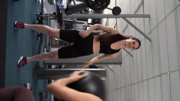 两名体格健康的年轻人在体育馆里穿着运动服 在运动课上与一个药丸一起锻炼 垂直录像 — 图库视频影像