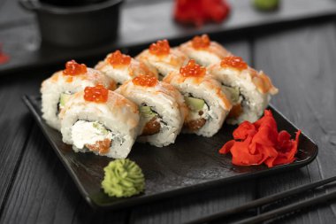 Japon mutfağı konsepti. Krem peynirli suşi rulosu ve karidesle kaplı somon balığı. Kırmızı havyarla süslenmiş. Yakın plan.