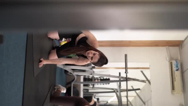 在健身房锻炼的年轻女人 女运动员早上在体育馆做伸展运动 垂直录像 — 图库视频影像