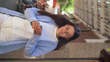 Şehir caddesinde yürürken gülümseyen ve kahve içen neşeli beyaz kadın, yakın plan. Dikey video