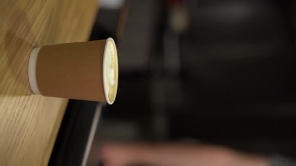 テーブルにテイクアウトのコーヒーカップを置くバリスタは それを取る クローズアップ バーティカルビデオ — ストック動画