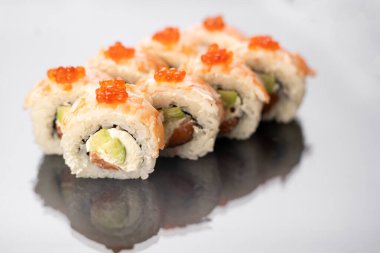 Sushi beyaz arkaplanda yansımalı yuvarlanıyor, metin için boşluk. Japon gıda konsepti