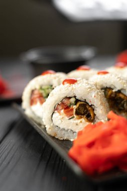 Kırmızı biber, yılan balığı ve üzerine susam tohumu serpiştirilmiş Philadelphia krem peyniri ile doldurulmuş beyaz suşi ruloları. Wasabi, zencefil ve soya sosuyla servis edilir. Boşluğu kopyala