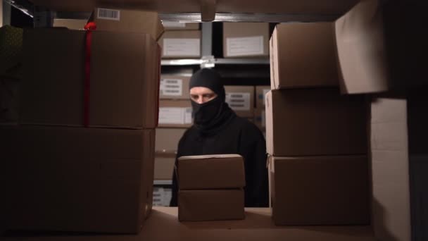 倉庫におけるセキュリティ問題の概念 黒いマスクの泥棒は夜に倉庫で箱を盗む コピースペース — ストック動画
